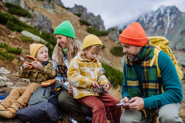 Happy family resting, having snack during hiking together in an autumn mountains. - HPIF33534
