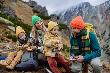 Glückliche Familie, die sich ausruht und bei einer Wanderung in den herbstlichen Bergen eine Kleinigkeit isst. - HPIF33535