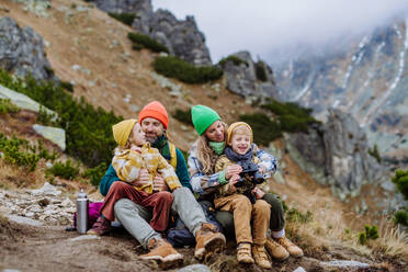 Happy family sitting and resting, during hiking together in an autumn mountains. - HPIF33537