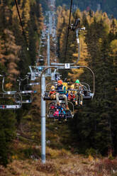 Familie sitzt in der Seilbahn und genießt die Aussicht. Berge mit geöffneter Seilbahn während der Touristensaison, - HPIF33559