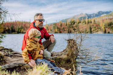 Glücklicher Vater mit seinem kleinen Sohn, der sich in der Nähe eines Sees in den Bergen ausruht. - HPIF33567