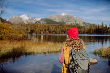 Rückansicht einer Frau, die am Ufer eines Sees in den Bergen steht. Eine weibliche Touristin genießt die Aussicht auf die Berge. - HPIF33575