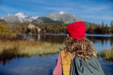 Rückansicht einer Frau, die am Ufer eines Sees in den Bergen steht. Eine weibliche Touristin genießt die Aussicht auf die Berge. - HPIF33576