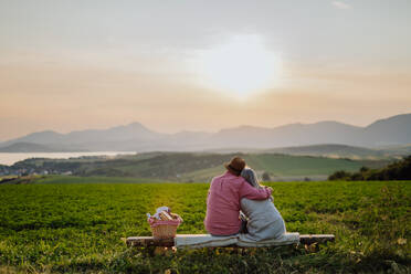 Umarmendes älteres Paar, das den Sonnenuntergang in der herbstlichen Natur beobachtet. Ältere Eheleute, die die ruhige Landschaft betrachten und die schöne Aussicht auf die Hohe Tatra genießen. - HPIF33589
