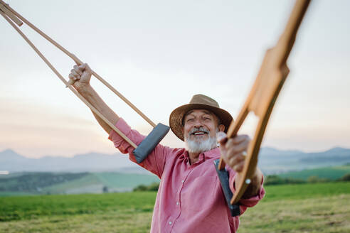 Senior man holding crutches in the air, he is happy about his recovery. Recovery, rehabilitation after injury or surgery in the nature. Concept of recovery and physical therapy - HPIF33600