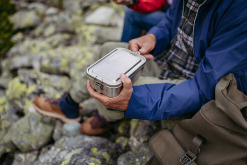 Nahaufnahme eines Snacks in der Lunchbox während einer Wanderung. Ein paar Touristen essen einen gesunden Snack, um Energie zu tanken. - HPIF33630