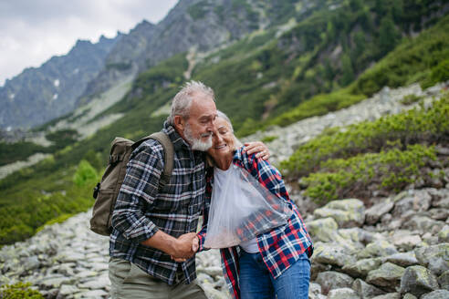 Älterer Mann hilft verletzter Frau. Eine ältere Frau verletzte sich beim Wandern in den Bergen am Arm. Die Touristin kam vom Weg ab und stürzte. - HPIF33649