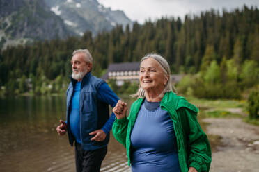 Älteres Ehepaar, das im Herbst am See joggt. Älteres Ehepaar, das in den Bergen Aktivurlaub macht und eine Kombination aus körperlicher Aktivität und Entspannung genießt. - HPIF33689