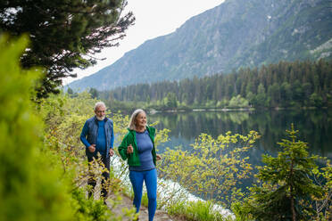 Älteres Ehepaar, das im Herbst am See joggt. Älteres Ehepaar, das in den Bergen Aktivurlaub macht und eine Kombination aus körperlicher Aktivität und Entspannung genießt. - HPIF33697