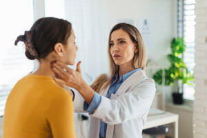 Ein Arzt untersucht die Lymphknoten am Hals eines Mädchens im Teenageralter. Konzept der Gesundheitsvorsorge für Jugendliche. - HPIF33700