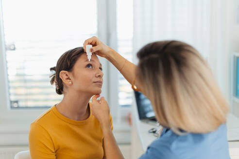 Ein Kinderarzt gibt Augentropfen in die Augen eines Mädchens. Ein Augenarzt behandelt eine Augeninfektion, Allergie oder Entzündung mit verschriebenen Augentropfen. - HPIF33704