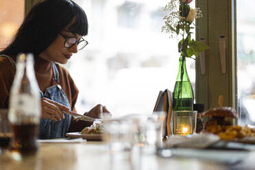 Woman having food at table in cafe - JCCMF10964