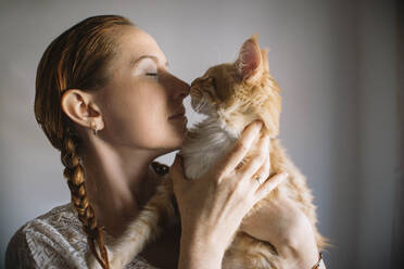Redhead woman embracing ginger cat at home - ASHF00033