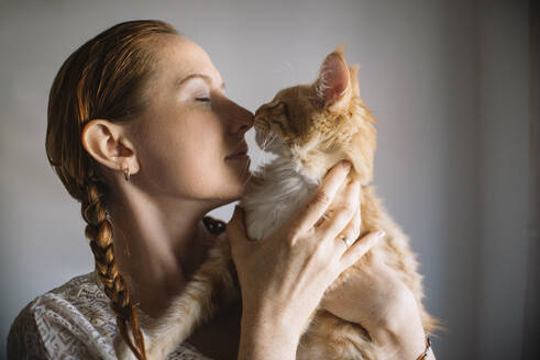 Redhead woman embracing ginger cat at home - ASHF00033