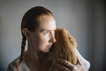 Redhead woman embracing cat at home - ASHF00035