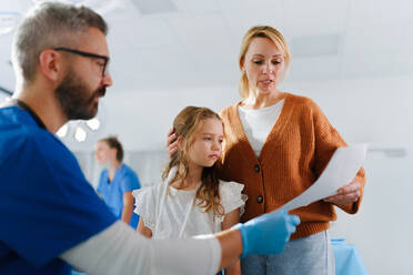 Ein Arzt erklärt der Mutter eines kleinen Mädchens mit verletztem Arm etwas. - HPIF33749