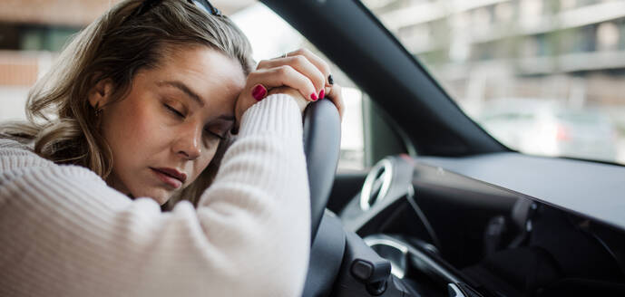 Portrait of young tired woman sleeping in a car, concept of safety and driving. - HPIF33807