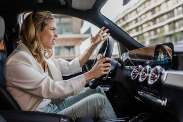 Upset woman driving her car in city. - HPIF33809