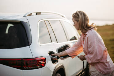 Woman charging the electric car, sustainable and economic transportation concept. - HPIF33829