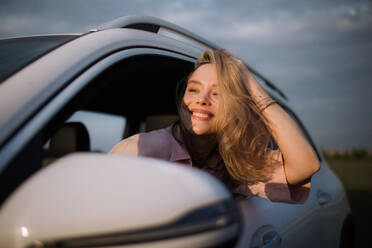 Happy woman driving her new electric car in a city. - HPIF33837