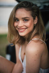 Portrait of beautiful woman sitting in car trunk. - HPIF33841