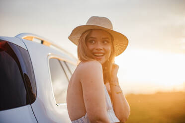 Portrait of young smiling woman standing near the car, enjoying summer time. - HPIF33845