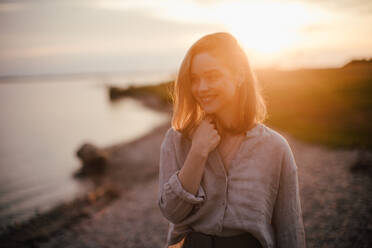 Young woman walking near the lake, enjoying summer time. - HPIF33855