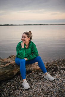 Portrait of happy woman in sportive clothes resting near a lake. - HPIF33862