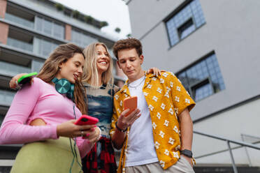 Generation z students hanging out together outdoors in the city. Young stylish zoomers are online, using smartphones, social media, taking selfies. Concept of power of friendship and social strength of gen Z. - HPIF33871