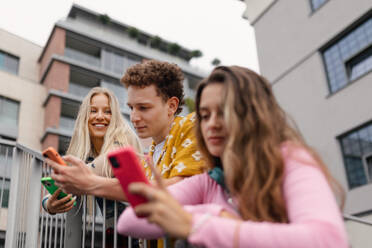 Generation z students hanging out together outdoors in the city. Young stylish zoomers are online, using smartphones, social media, taking selfies. Concept of power of friendship and social strength of gen Z. - HPIF33873