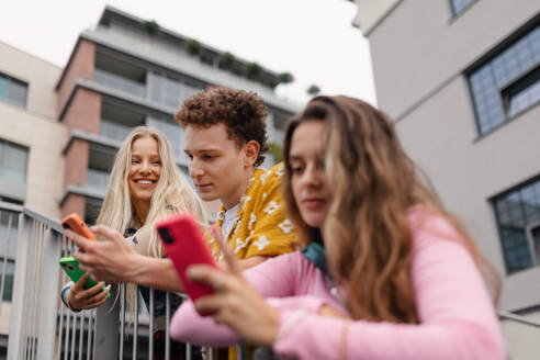 Generation z students hanging out together outdoors in the city. Young stylish zoomers are online, using smartphones, social media, taking selfies. Concept of power of friendship and social strength of gen Z. - HPIF33873