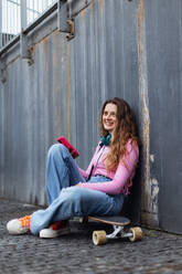 Portrait of generation z girl student sitting outdoors in the city. Student spending free time online and alone. Concept of gen Z as loneliest generation. - HPIF33878