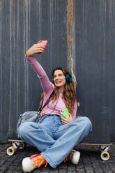 Portrait of generation z girl student sitting outdoors in the city and taking selfie. Student spending free time online and alone. Concept of gen Z as loneliest generation. - HPIF33880