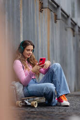 Porträt einer Studentin der Generation Z, die im Freien in der Stadt sitzt. Die Studentin verbringt ihre Freizeit online und allein. Konzept der Generation Z als einsamste Generation. - HPIF33881