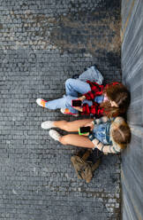 Top view of young stylish generation Z girls studying together outdoors after school. Young female zoomers talking and gossiping during lunch break in the school. Concept of power of friendship and importance of education for gen Z. - HPIF33885