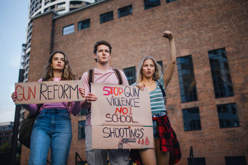 Aktivisten der Generation Z protestieren mit Transparenten auf der Straße. Junge Zoomer-Studenten, die durch die Stadt marschieren und gegen den Klimawandel demonstrieren. Demonstranten, die Waffenkontrolle, Rassen- und Geschlechtergleichheit fordern. Konzept der Macht der Freundschaft und der sozialen Stärke der Generation Z. - HPIF33896