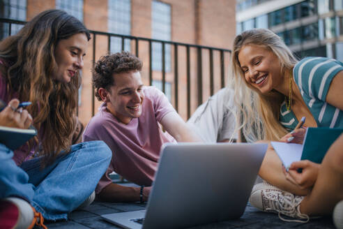 Group of generation Z students studying together outdoors after school. Young stylish zoomers working together on school project, preparing a presentation. Concept of power of friendship and importance of education of gen Z. - HPIF33902