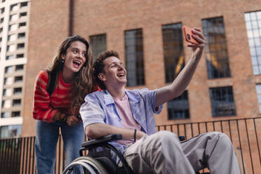 Handsome gen Z boy in a wheelchair with friends in the city. Inclusion, equality, and diversity among Generation Z. - HPIF33909