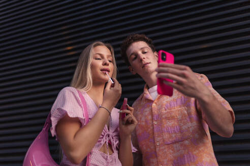 Gen Z couple in pink outfit taking selfie before going the cinema to watch movie. The young zoomer girl and boy watched a movie addressing the topic of women, her position in the world, and body image. - HPIF33918