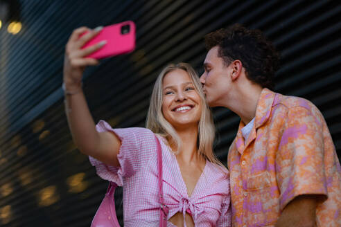 Gen Z couple in pink outfit taking selfie before going the cinema to watch movie. The young zoomer girl and boy watched a movie addressing the topic of women, her position in the world, and body image. - HPIF33920