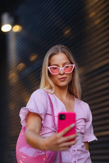 Gen Z girl in pink outfit taking selfie before going the cinema to watch movie. The young zoomer girl watched a movie addressing the topic of women, her position in the world, and body image. - HPIF33922