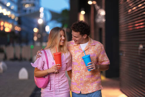 Ein Gen Z-Paar in pinken Outfits verlässt das Kino mit einem Getränk in der Hand. Die jungen Zoomer sahen sich einen Film an, der sich mit dem Thema Frauen, ihrer Stellung in der Welt und ihrem Körperbild befasste. - HPIF33923
