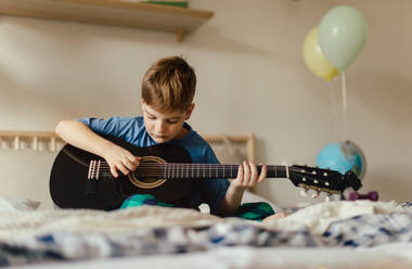 Happy boy playing on the guitar in the room. - HPIF33936