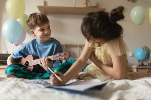 Sister and brother spend quality time together. Happy friends playing on the musical instuments and do the homework together. - HPIF33954