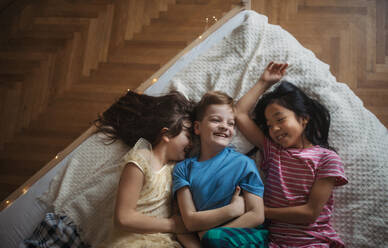 Top view of three happy friends lying in bed. - HPIF33962