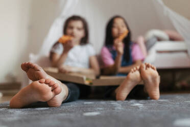 Friends sit on the floor with pizza box in their lap. Eating food in the bedroom. - HPIF34002