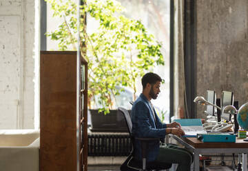 Young man sitting in an office and working. - HPIF34009