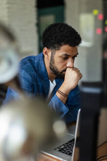 Young tired man sitting in front of laptop in his office. - HPIF34023