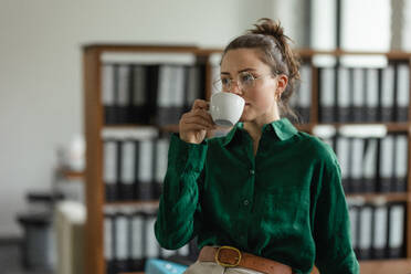 Portrait of young woman with cup of coffee in the office. - HPIF34060