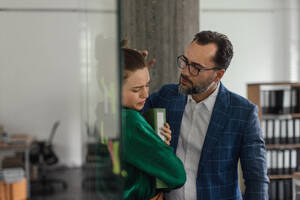 Mature man abusing his younger colleague, concept of harassment at work. Young female feeling under pressure, lacking personal space. - HPIF34084